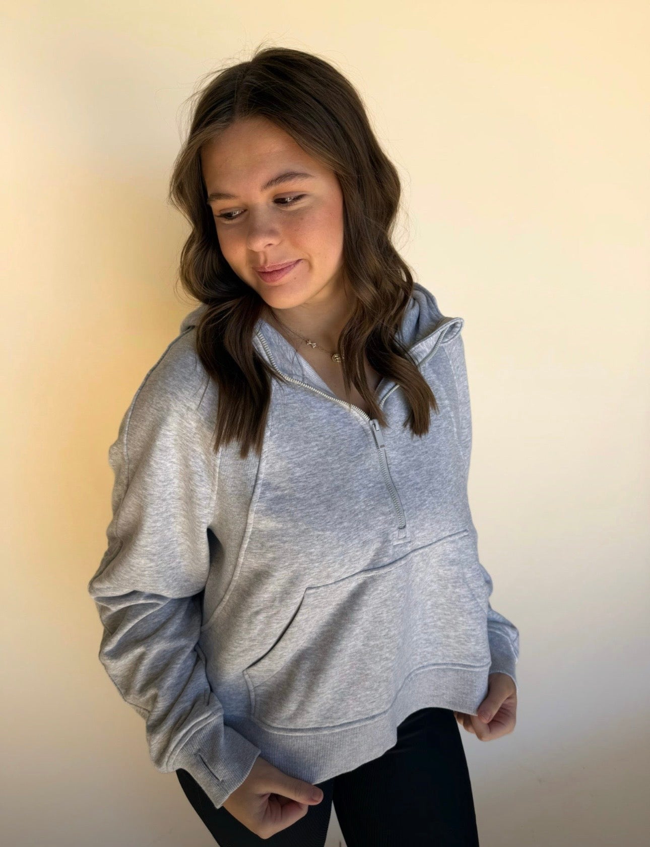 Woman wearing a gray hoodie against a plain background