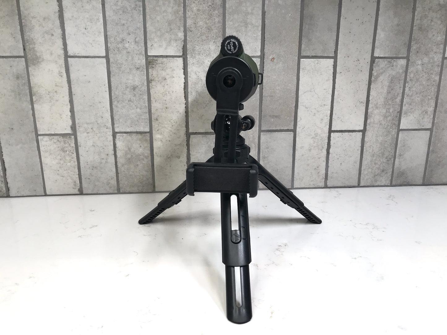 Black tripod with camera mount on a white surface against a tiled wall background Cole Wheeler