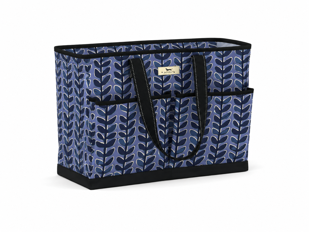 A rectangular utility tote bag with a blue and navy leaf pattern, black handles, and a small gold brand plaque on the front, set against a plain white background.