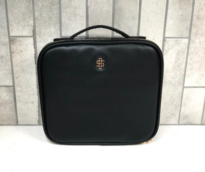 Black travel cosmetic case with a logo on a tiled wall background
