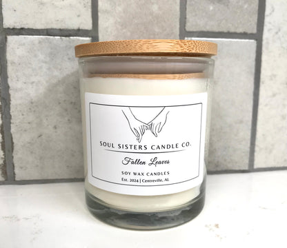 Scented candle with wooden lid and 'Soul Sisters Candle Co' label on a tiled wall background