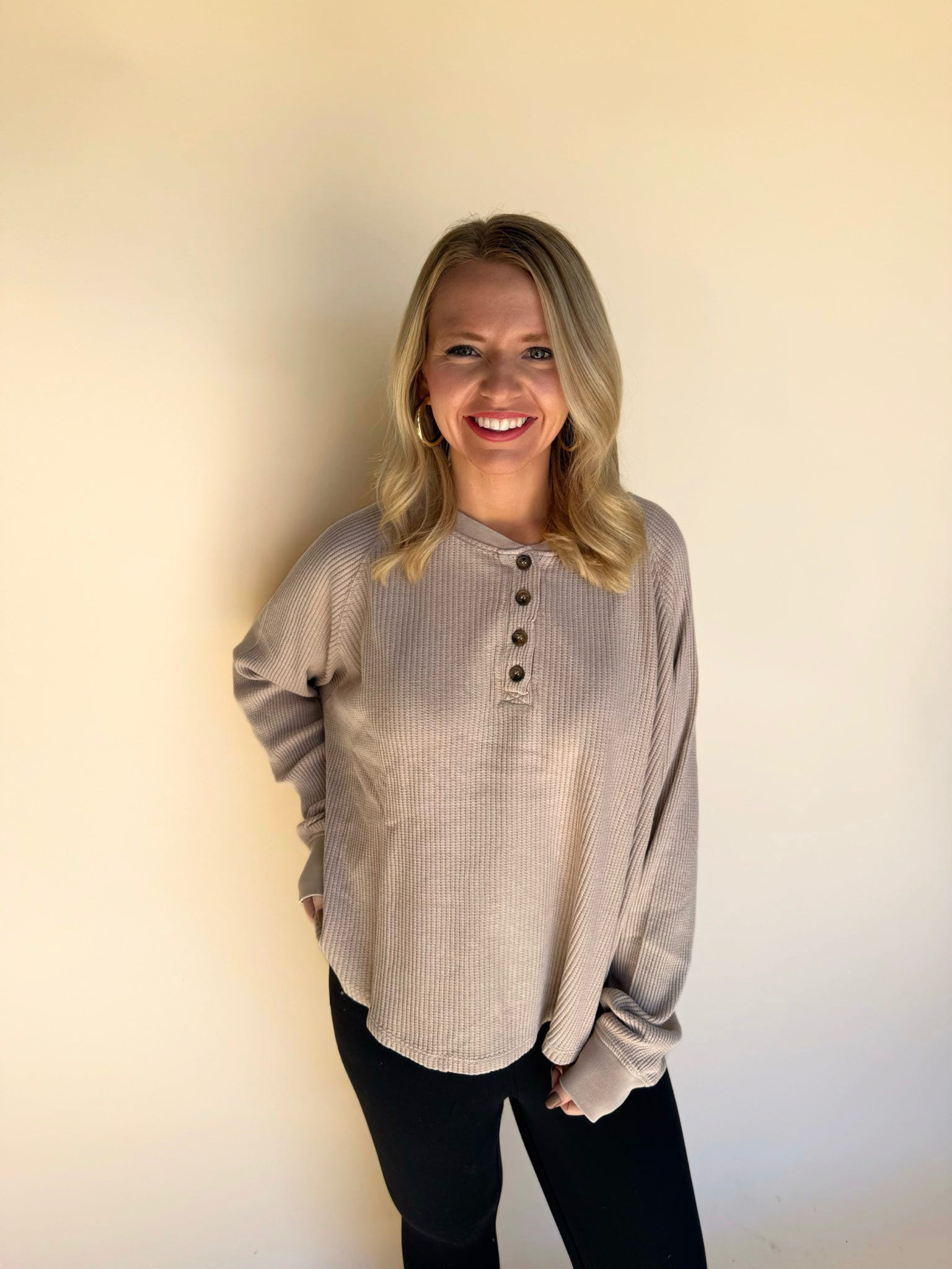 Woman wearing a dark taupe long-sleeve shirt with buttons against a plain background