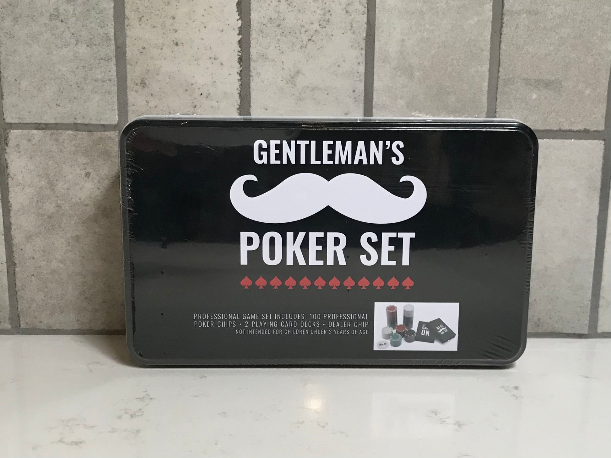 Gentleman's Poker Set packaging with a mustache logo on a tiled floor.