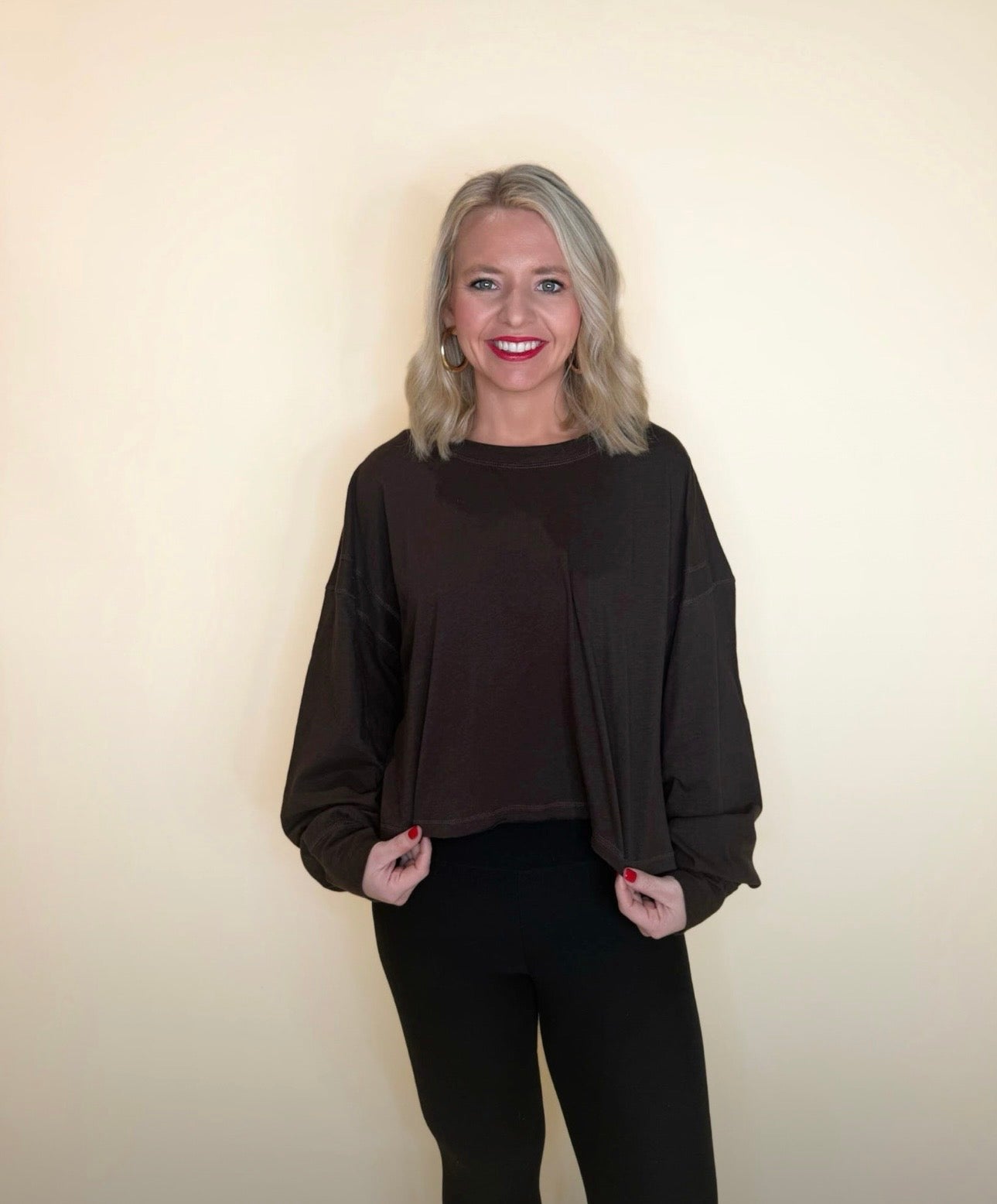 Woman wearing a dark brown oversized long sleeve top with black pants, loose lightweight knit for cozy casual style.