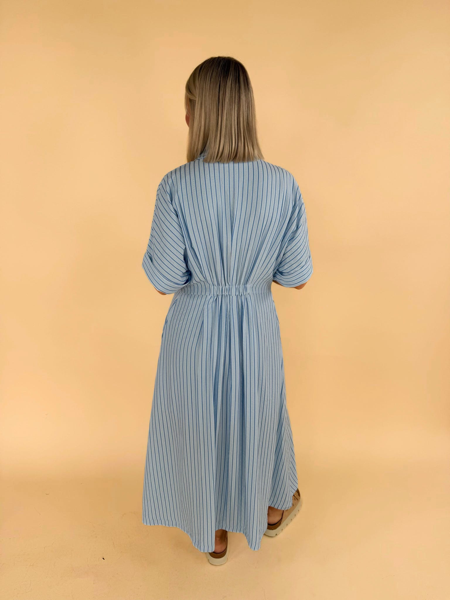 Back view of light blue striped midi shirt dress with elastic waist women’s boutique fashion