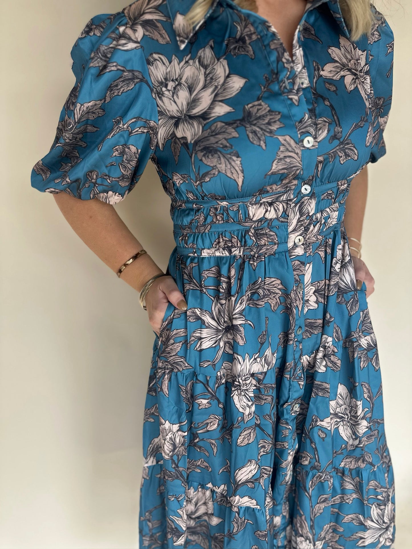 Blue floral dress worn by a person against a plain background