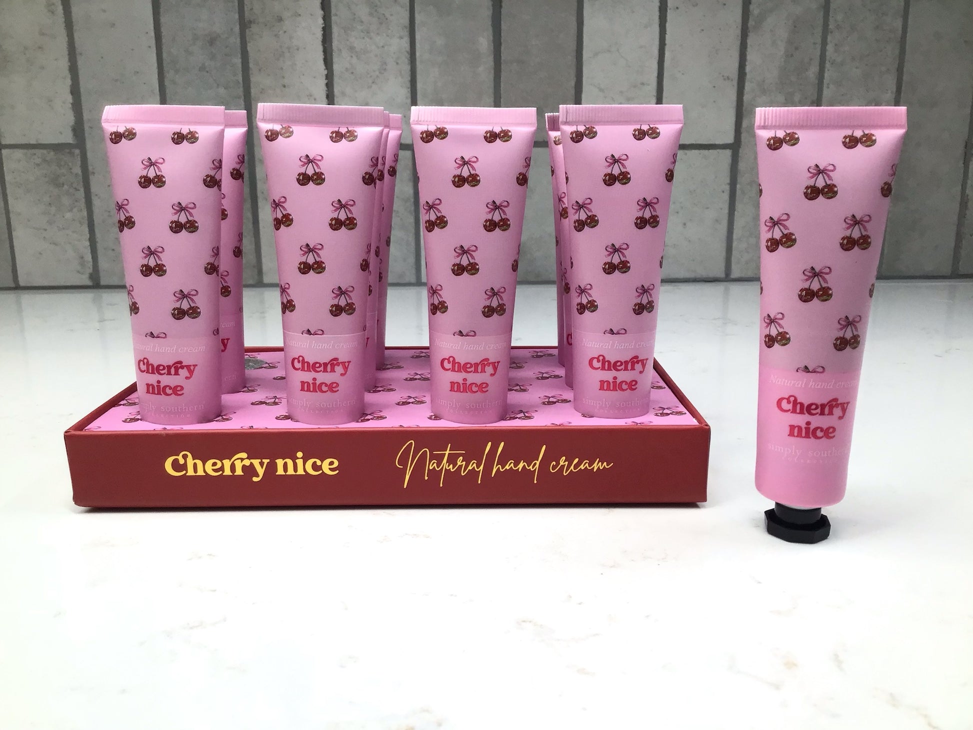 Set of 'Cherry nice' hand cream with pink packaging and cherry design on a white background.