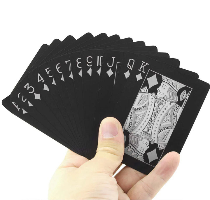 Hand holding the Mad Man Waterproof Black Edition plastic playing cards fanned out to showcase the durable waterproof black card design