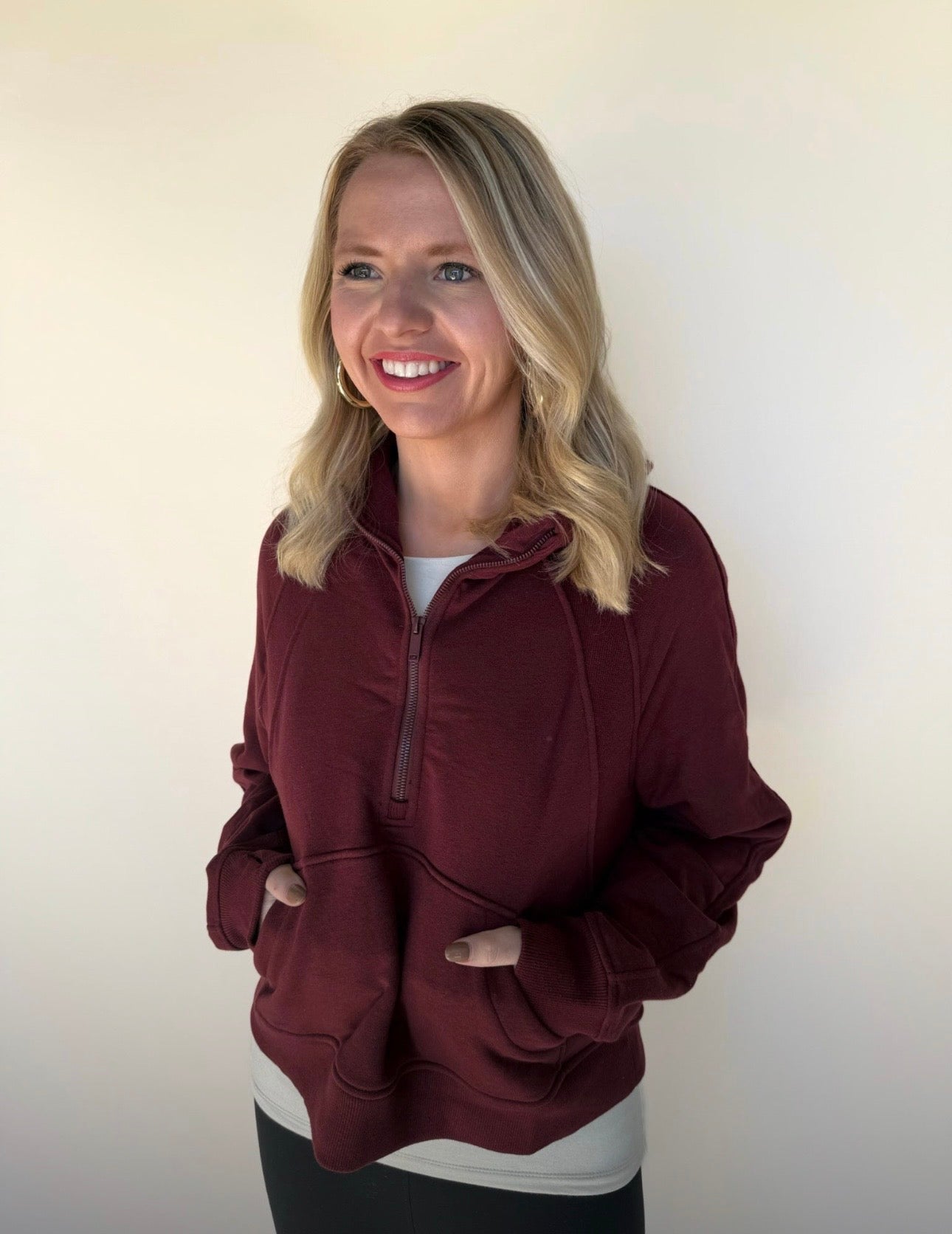 Woman wearing a burgundy pullover with a white background
