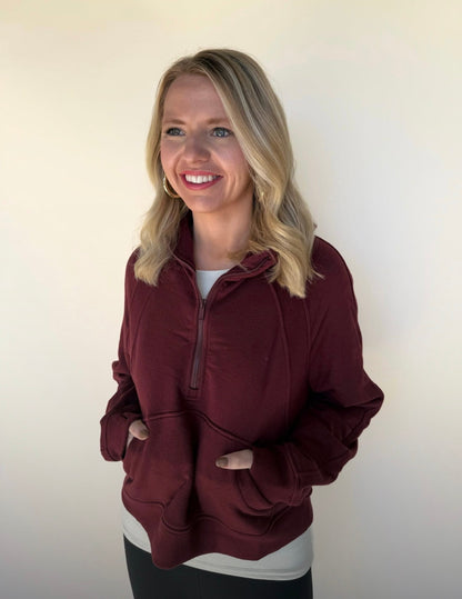 Woman wearing a burgundy pullover with a white background
