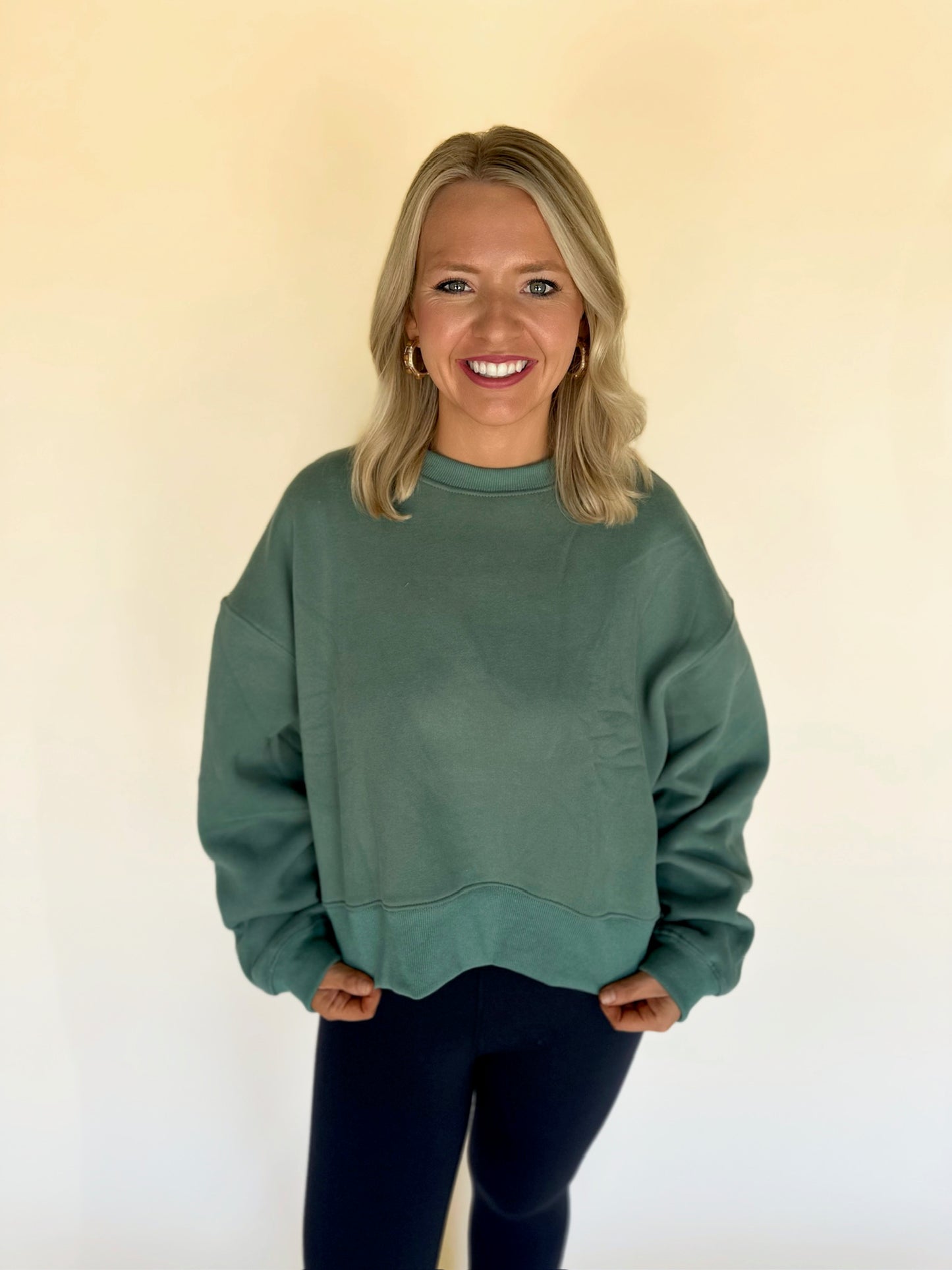 Woman wearing a green sweatshirt against a plain background