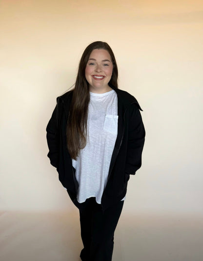 Person wearing a black jacket over a white shirt against a plain background