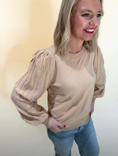 Side view of beige puff sleeve sweater with ribbed pleated sleeves, styled Casual with light wash jeans.