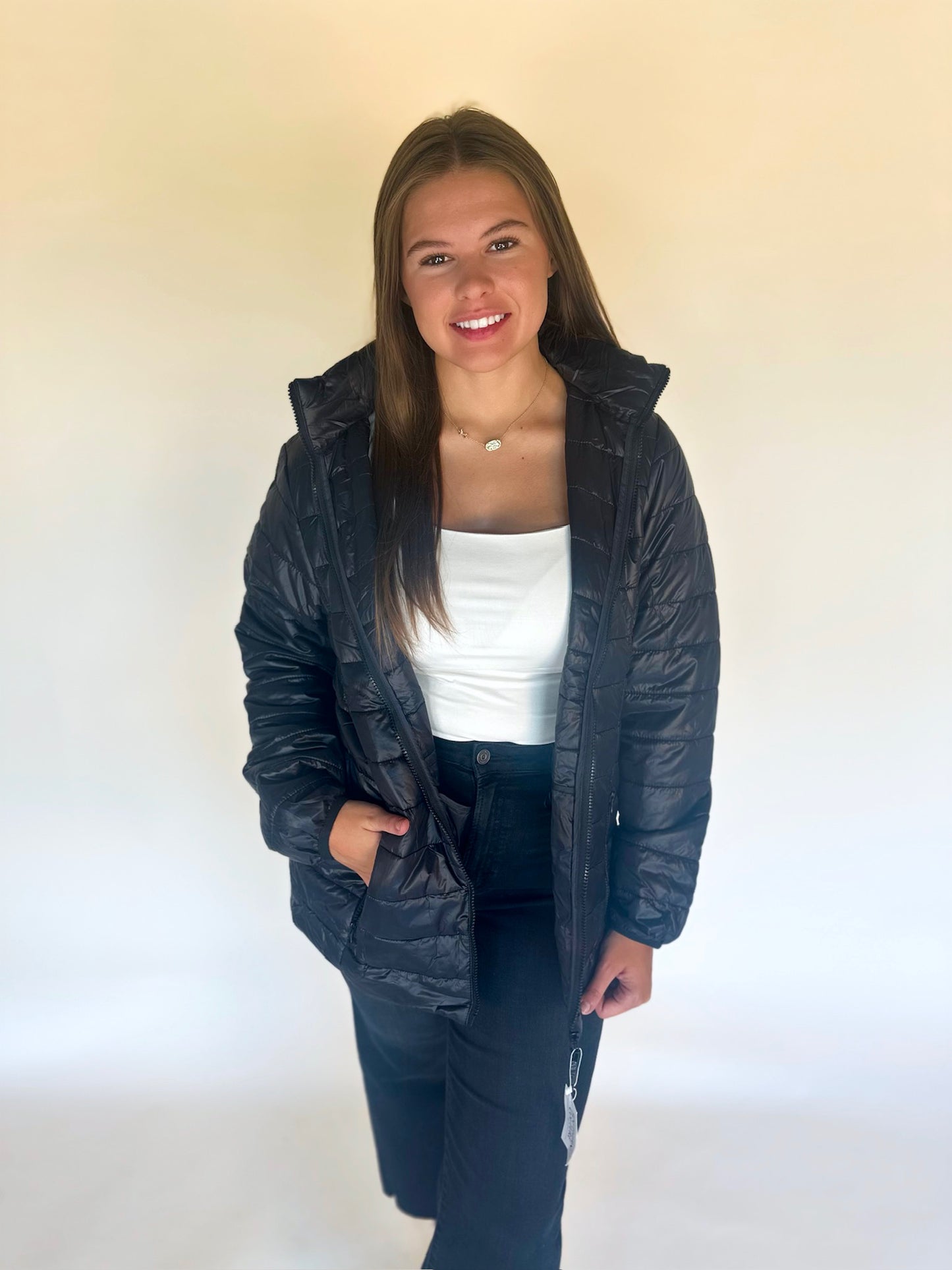 Person wearing a black puffer jacket over a white shirt on a plain background