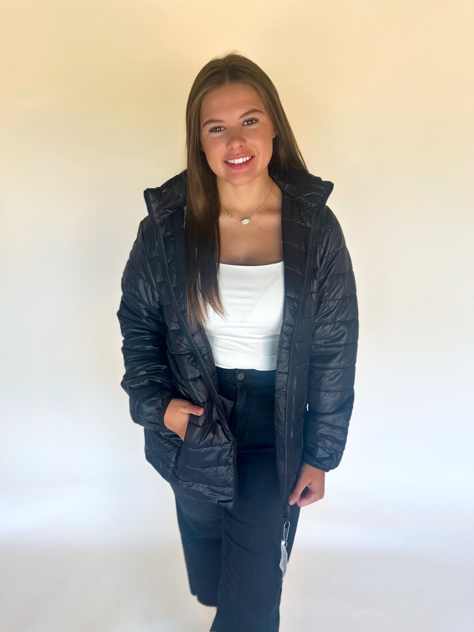 Person wearing a black puffer jacket over a white shirt on a plain background