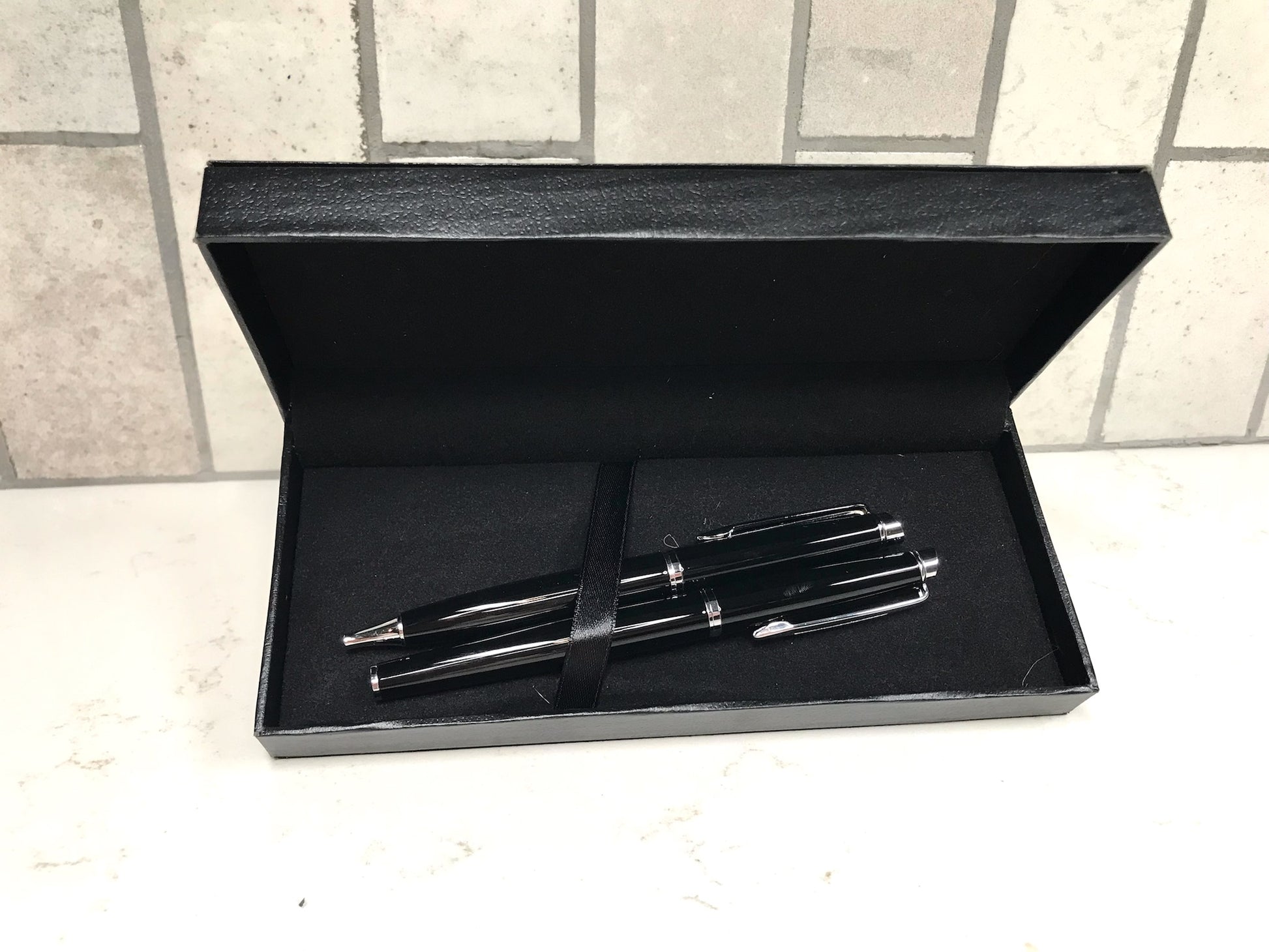 Set of pens in a black box on a tiled floor