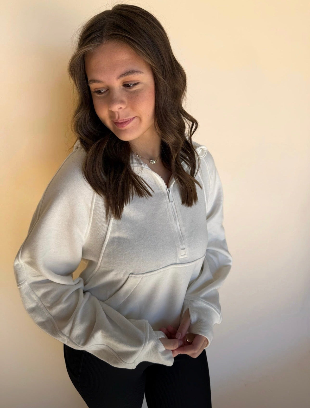 Person wearing a off white jacket against a plain background