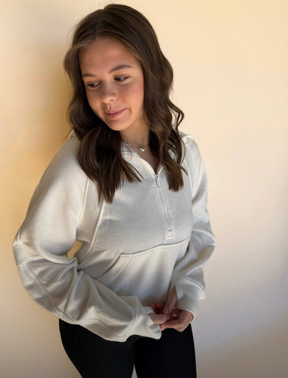 Person wearing a off white jacket against a plain background