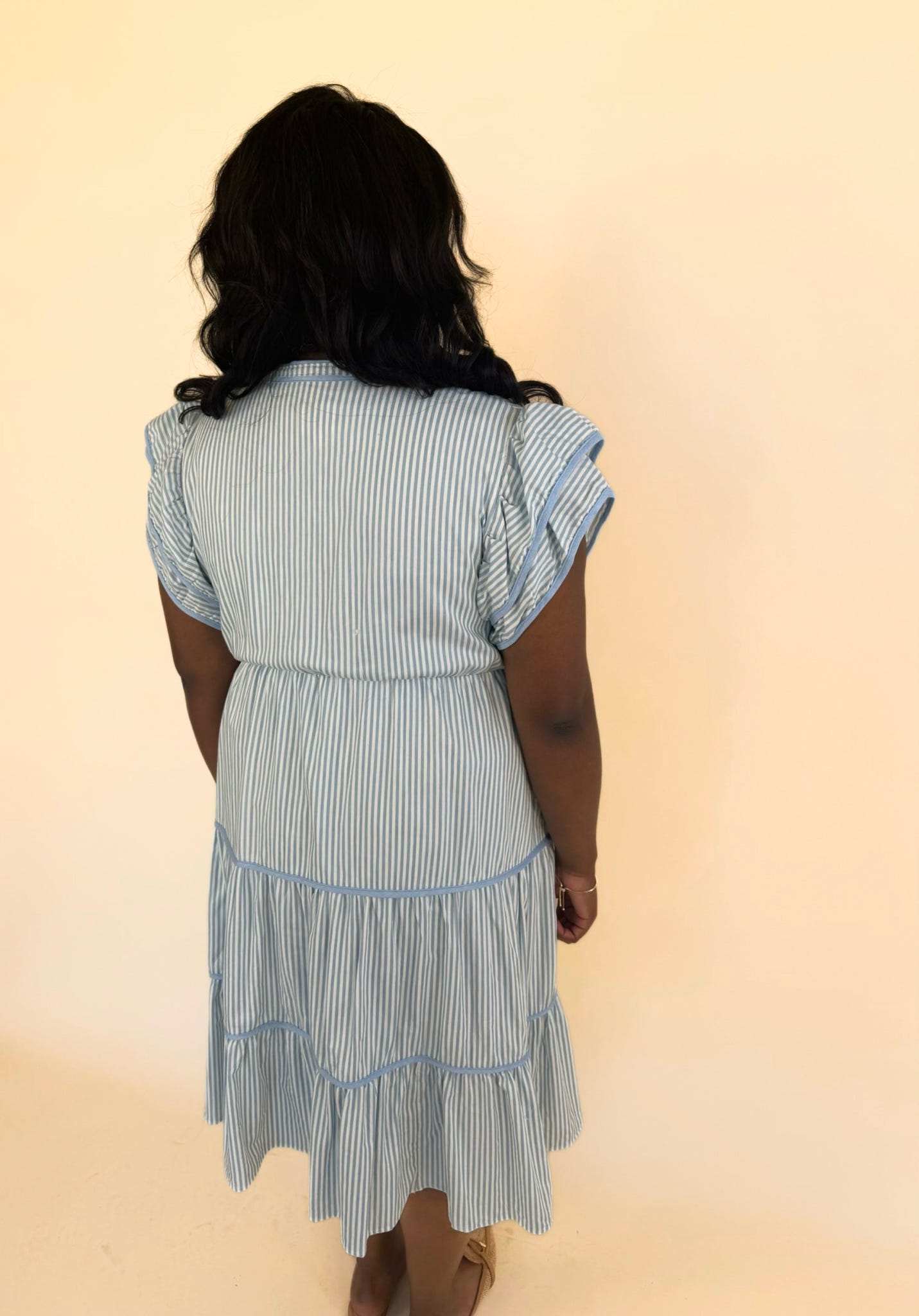 Back view of plus size blue pinstripe tiered midi dress with flutter sleeves and relaxed fit, casual women’s boutique dress
