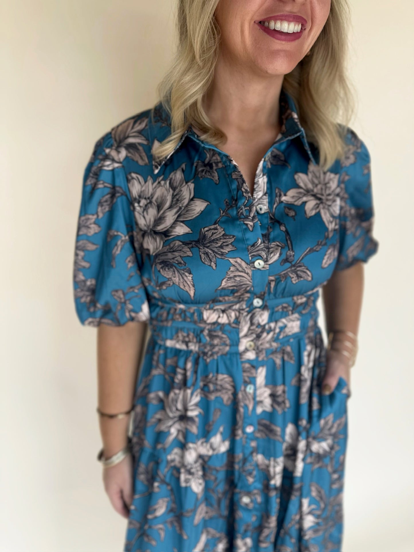 Woman wearing a blue floral dress against a plain background