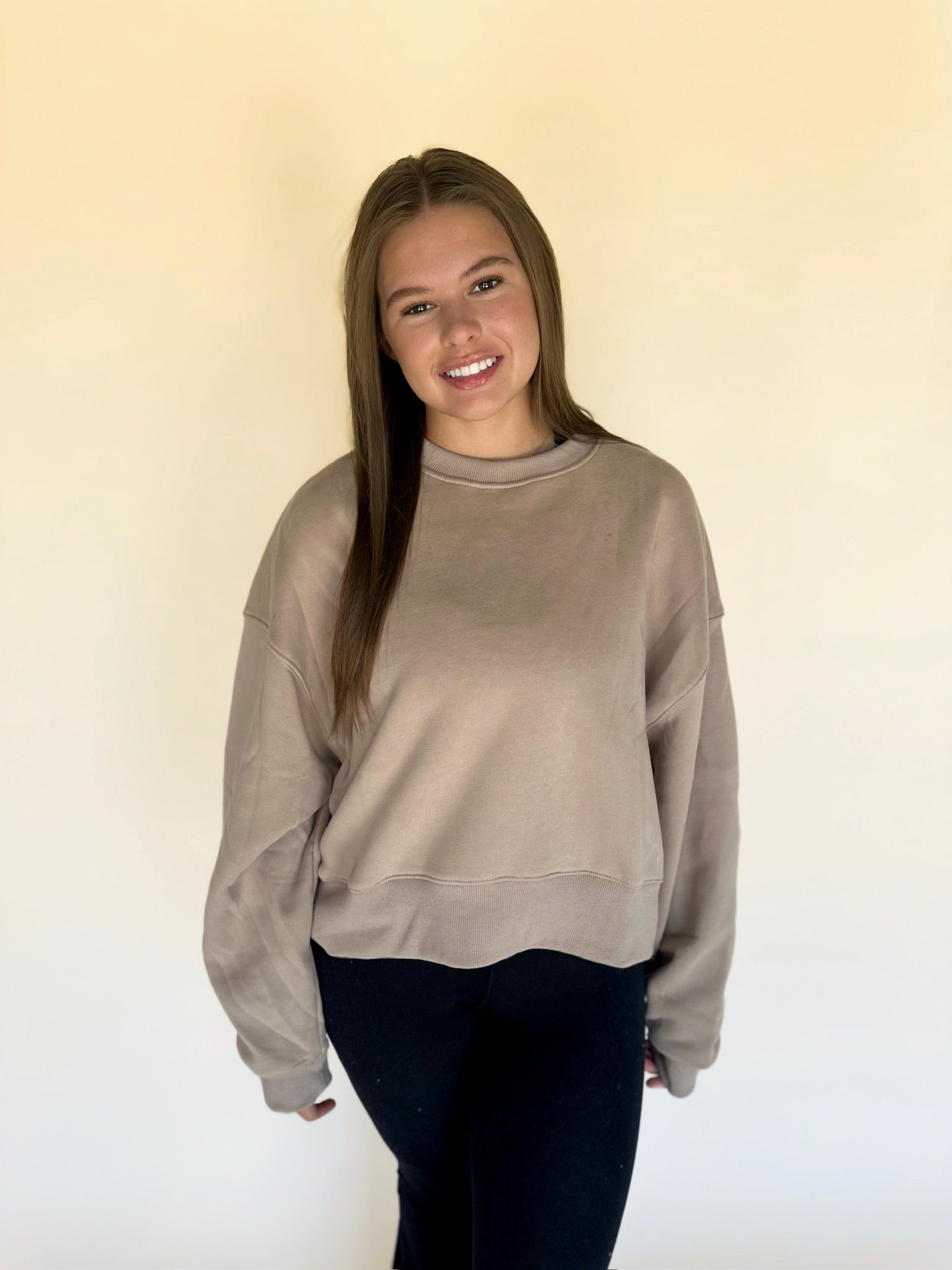 Woman wearing a beige sweatshirt against a plain background