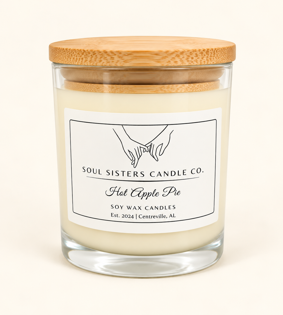 Soul Sisters Candle Co. Hot Apple Pie soy wax candle in a clear glass jar with natural wood lid and white label, featuring an apple and warm baking spice fragrance.