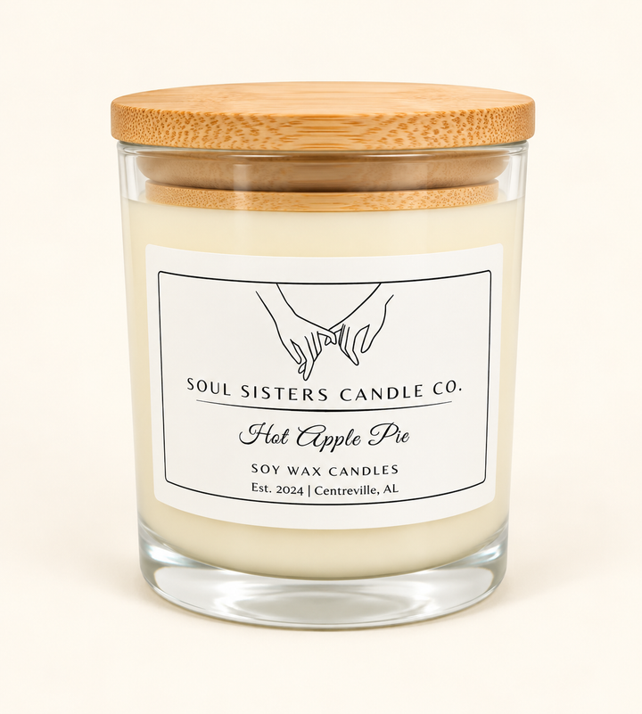 Soul Sisters Candle Co. Hot Apple Pie soy wax candle in a clear glass jar with natural wood lid and white label, featuring an apple and warm baking spice fragrance.