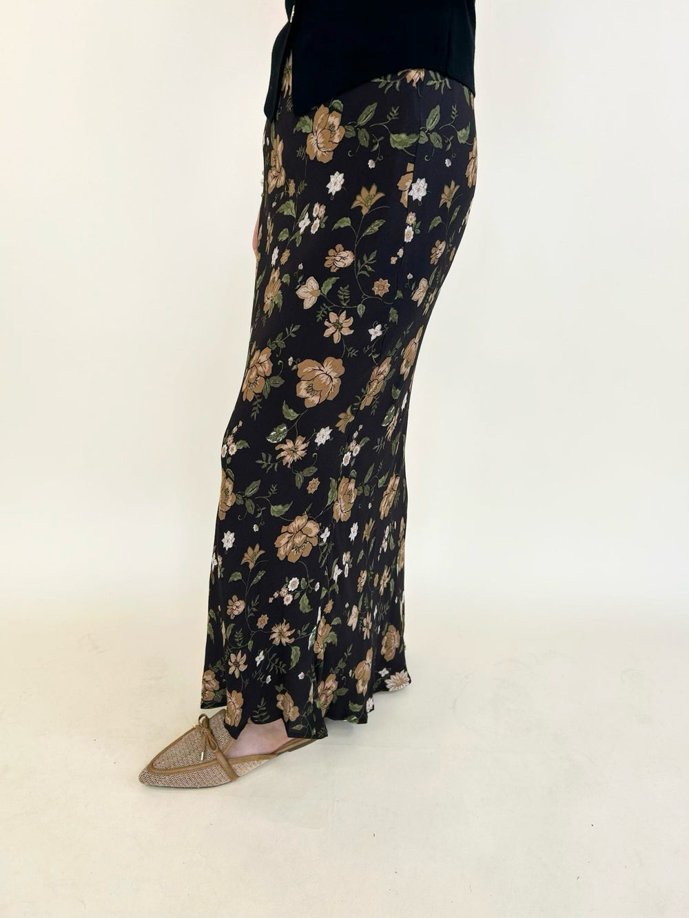 Side view of the Elaina Floral Slip-On Midi Skirt featuring a black floral print, flowy midi length, and slip-on elastic waistband.