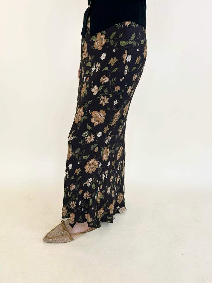 Side view of the Elaina Floral Slip-On Midi Skirt featuring a black floral print, flowy midi length, and slip-on elastic waistband.