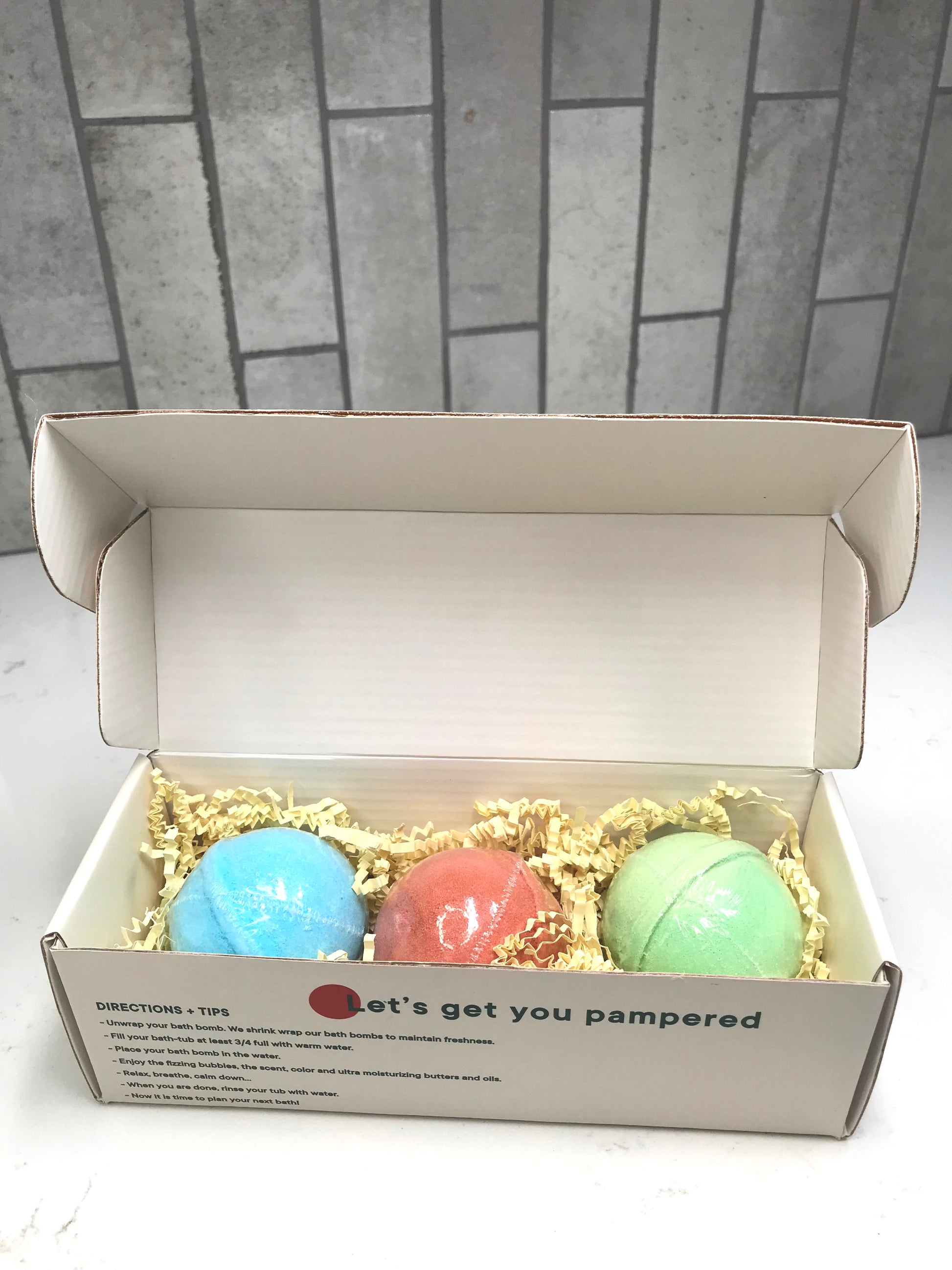 Three bath bombs in a box with a message on a tiled floor background