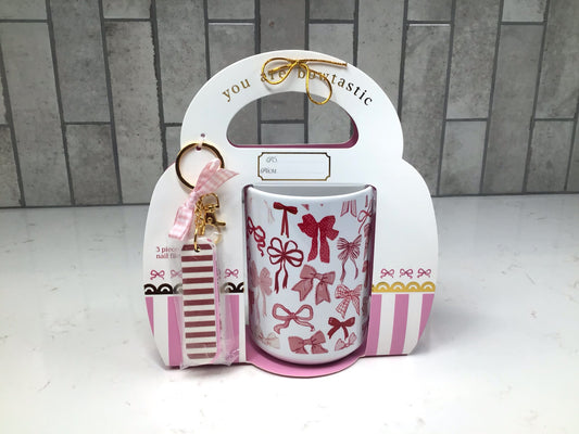 Pink bow-pattern ceramic mug packaged in holiday gift box with striped nail file keychain and pink ribbon.