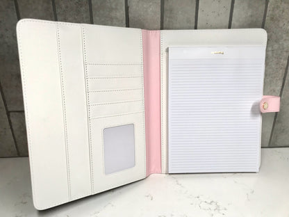 White notebook with pink accents on a marble surface