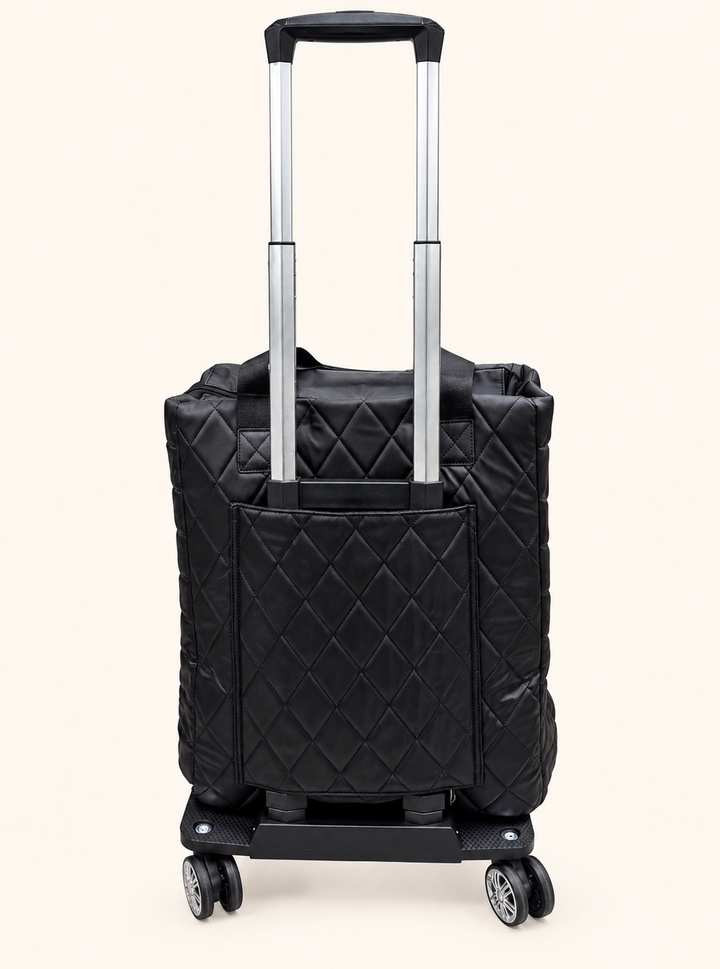 Back view of Simply Southern black quilted rolling travel tote featuring an extended telescoping handle, rear pocket, and swivel wheels.
 Copy