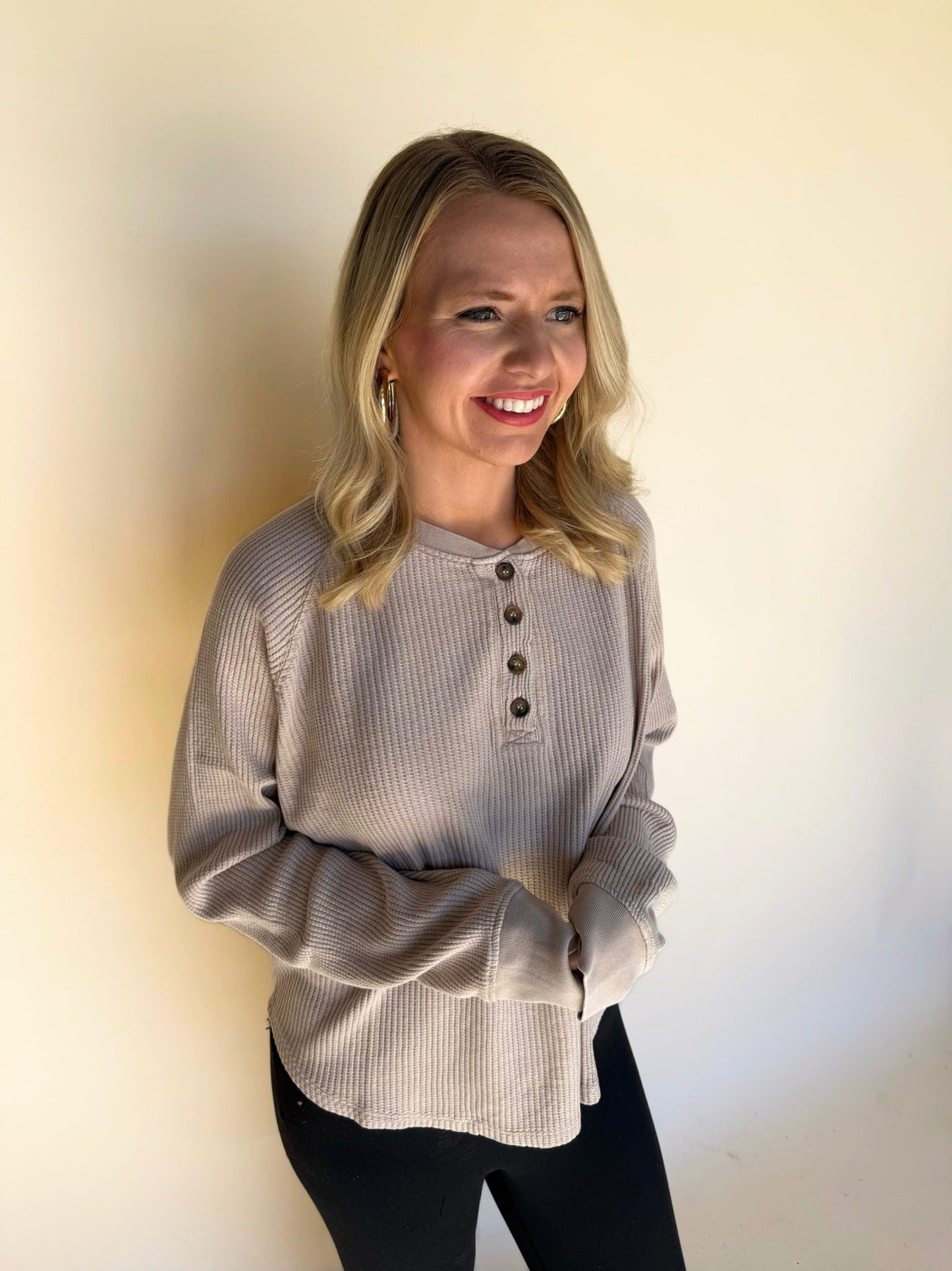 Woman wearing a dark taupe ribbed sweater against a plain background