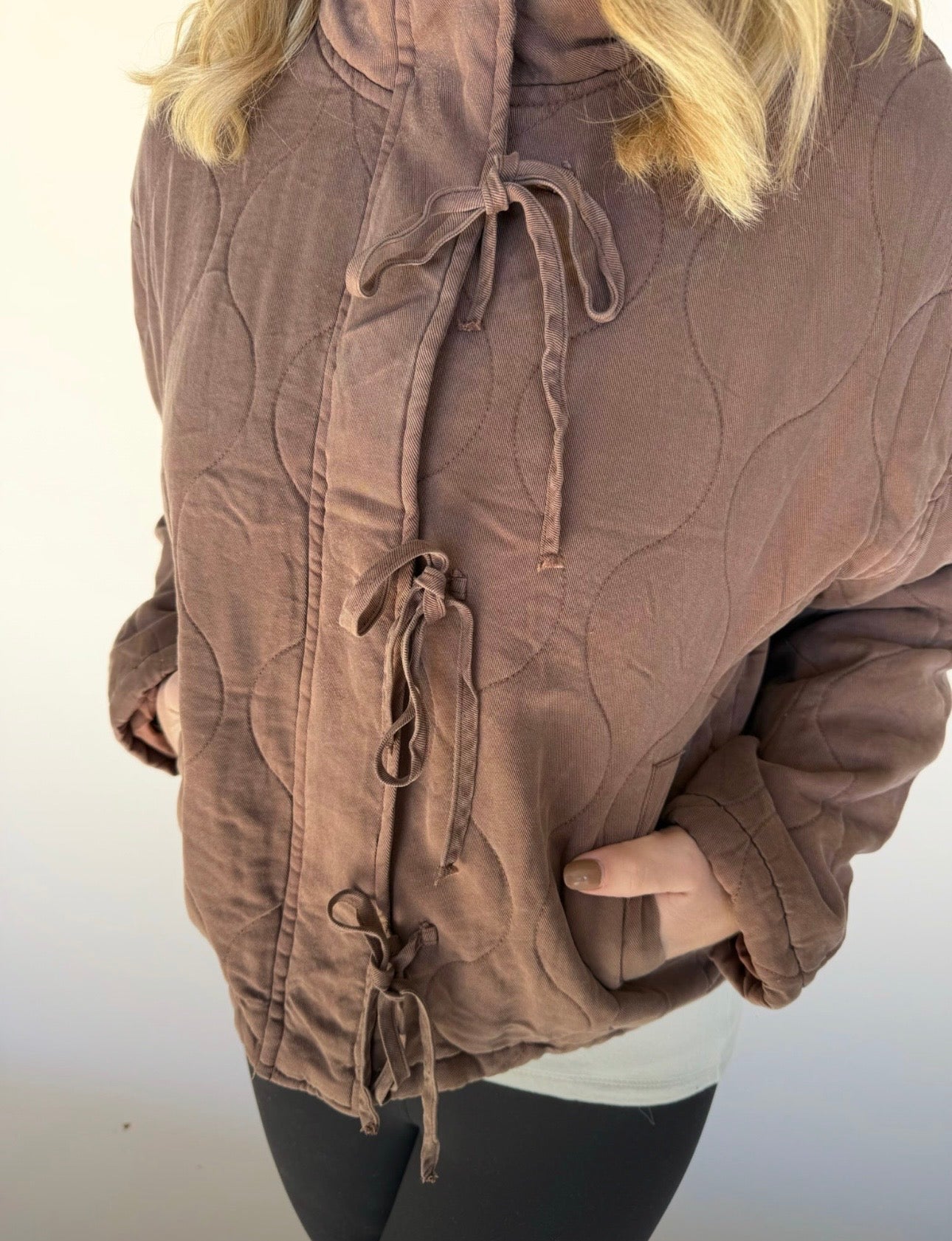 Brown textured jacket with drawstrings on a plain background