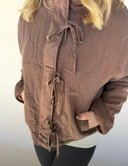 Brown textured jacket with drawstrings on a plain background