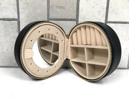 Round jewelry case with mirror on a tiled floor background