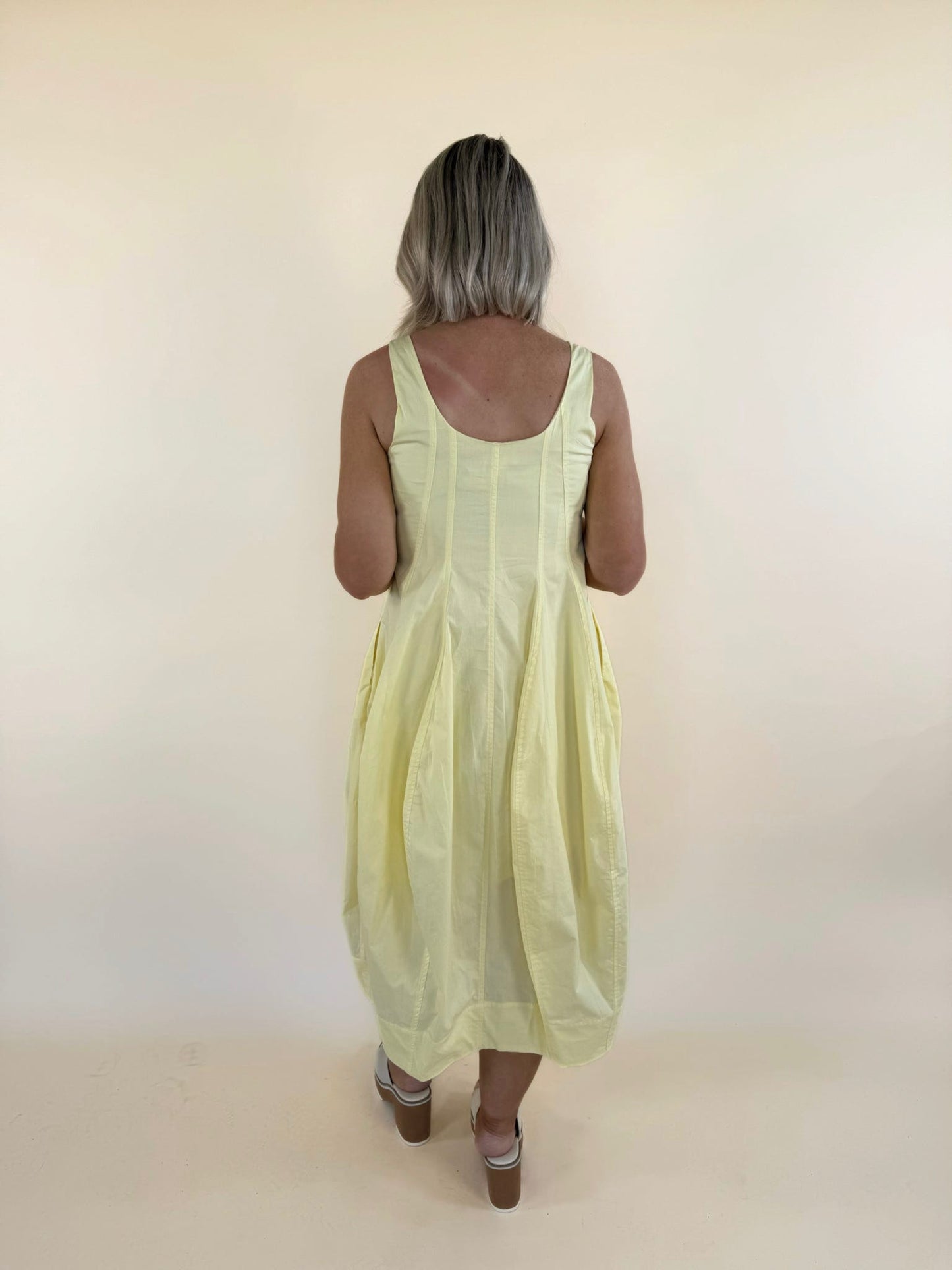 Back view of butter yellow tulip hem midi dress with flowy skirt and sleeveless design
