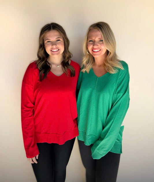 Two women wearing red and green shirts standing against a plain background