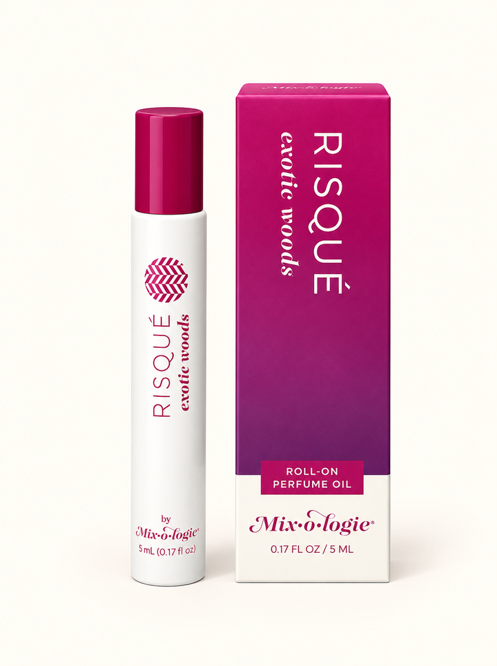 Mixologie Risqué Exotic Woods 5 mL rollerball perfume oil with magenta cap and purple gradient fragrance box on a cream background.