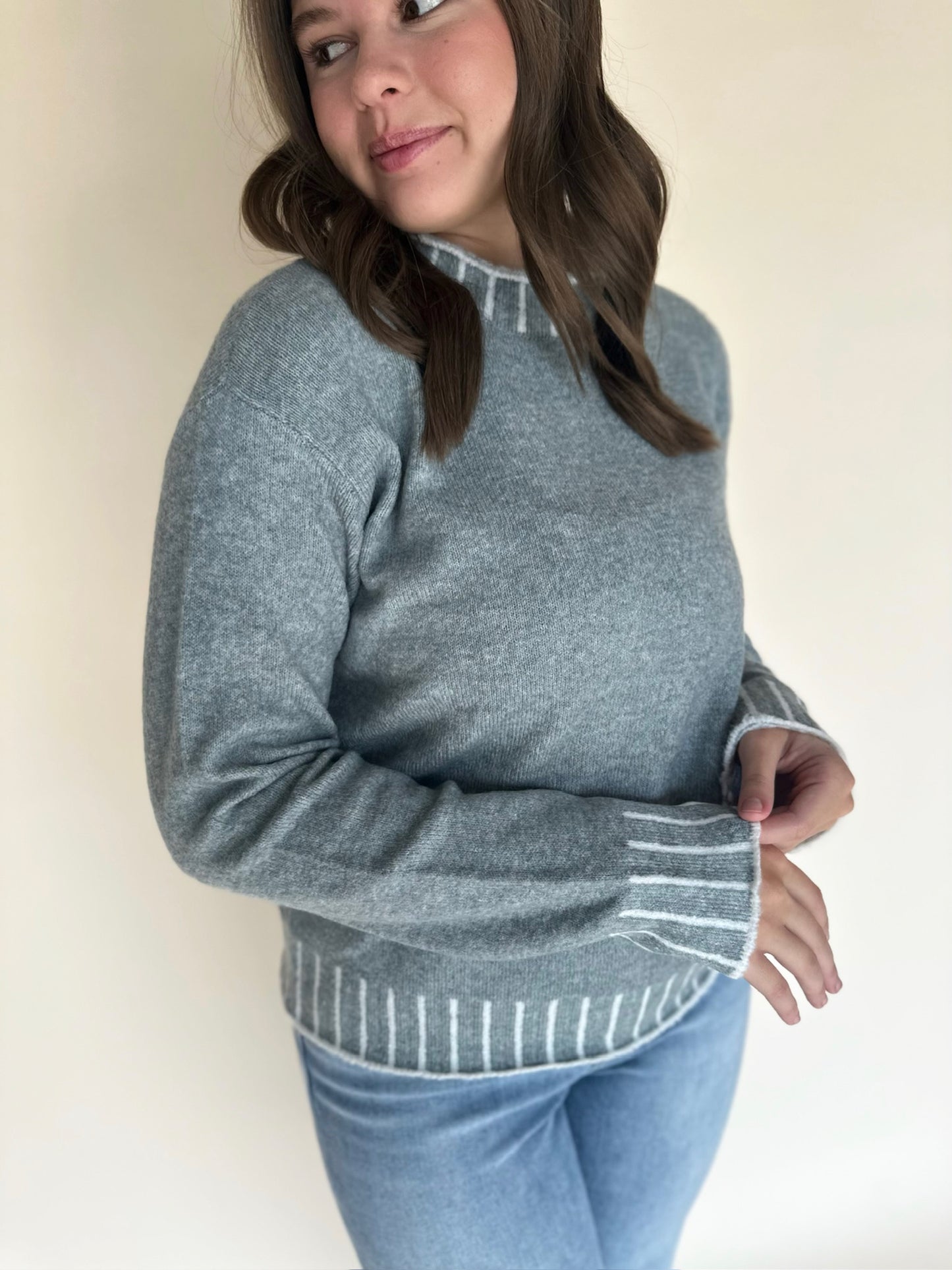 Person wearing a light blue sweater with a plain background