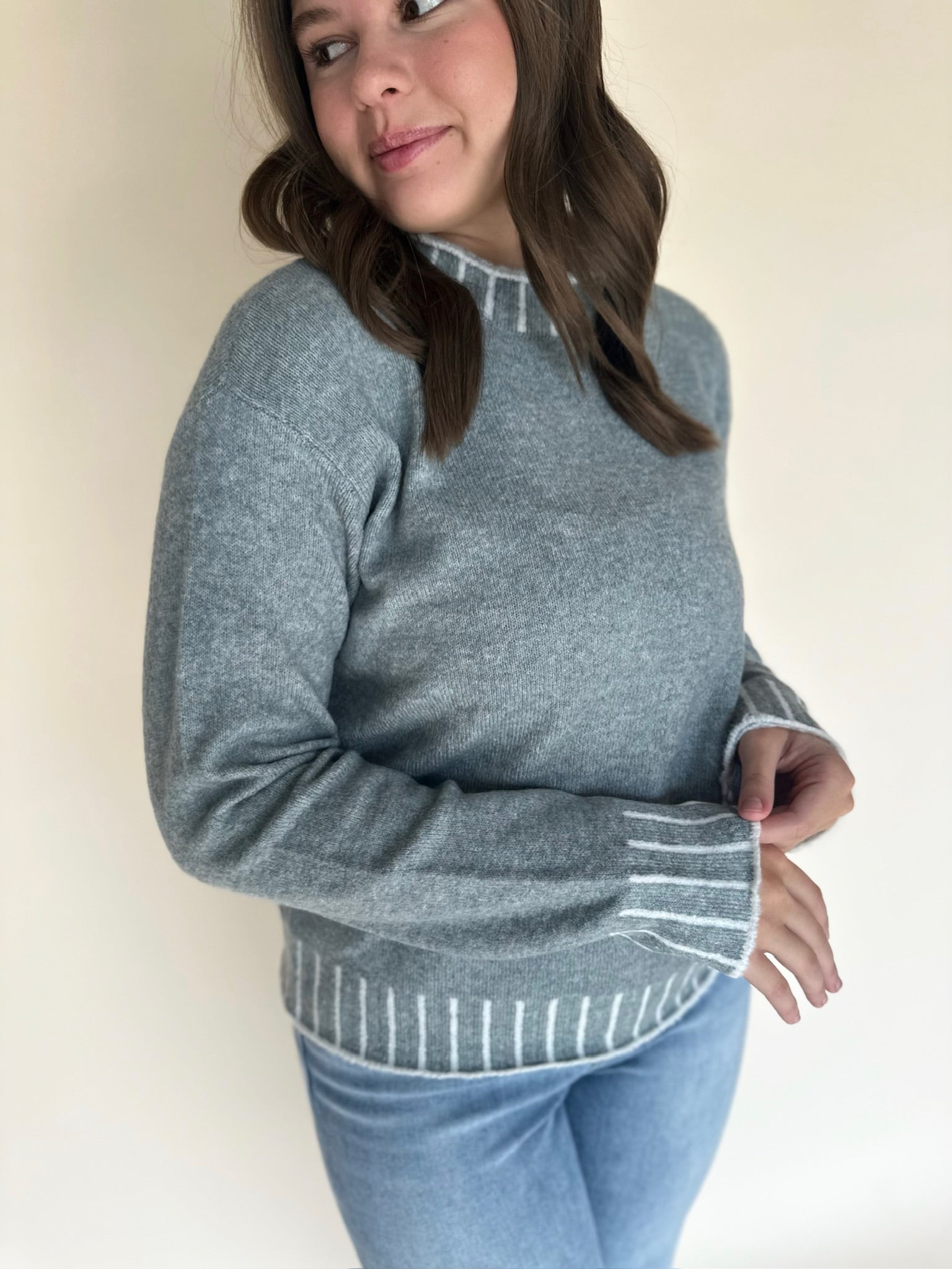 Person wearing a light blue sweater with a plain background