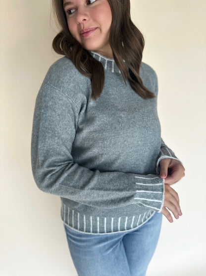 Person wearing a light blue sweater with a plain background