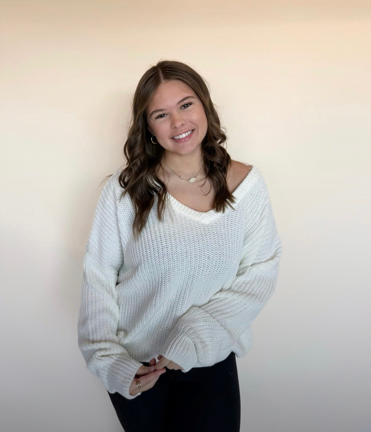 Woman wearing a white sweater against a plain background