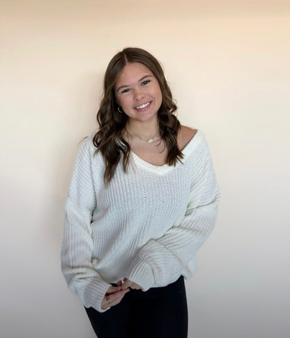 Woman wearing a white sweater against a plain background