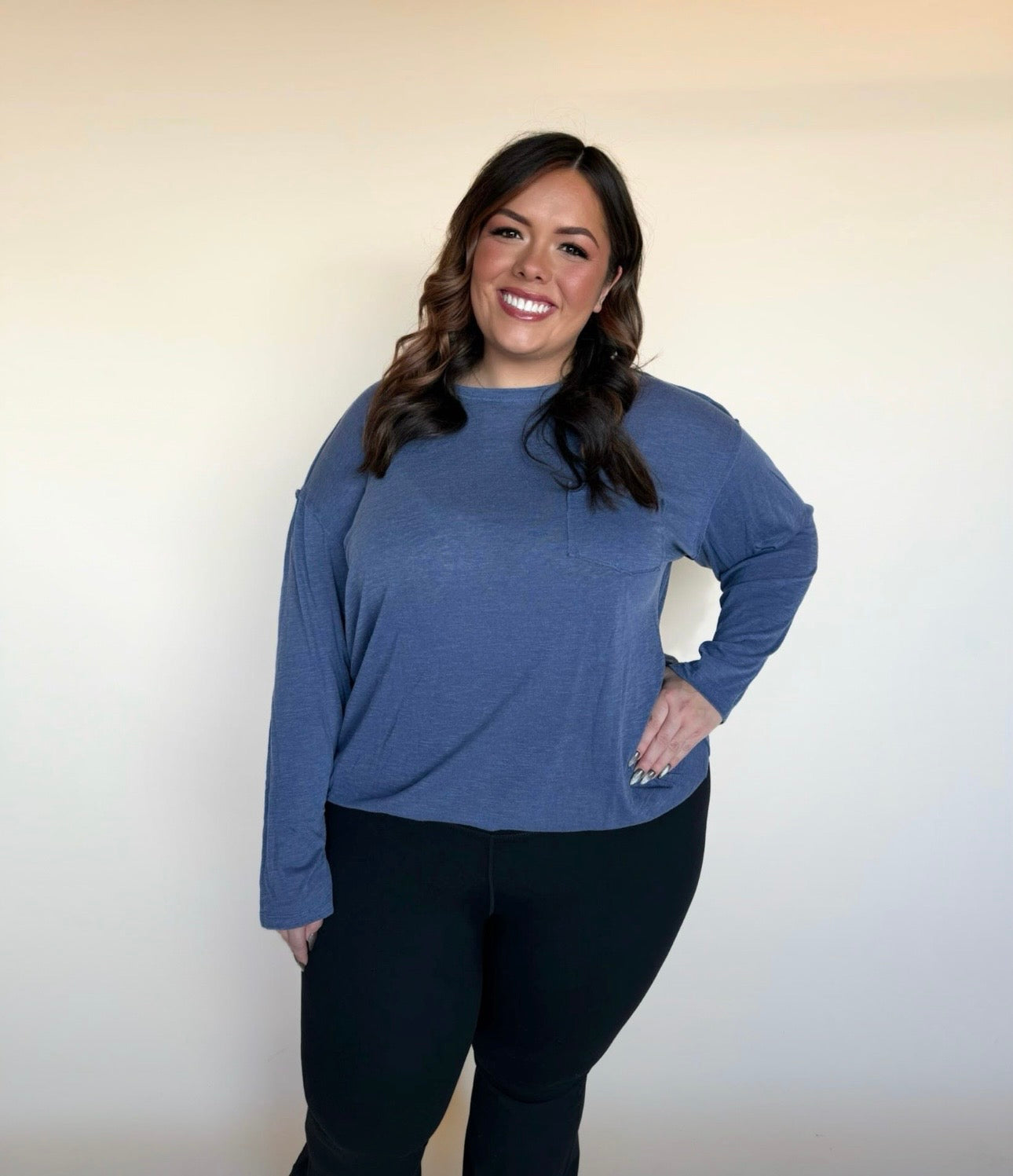Woman wearing a blue long-sleeve top against a plain background