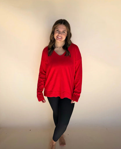 Person wearing a red sweater and black leggings against a plain background