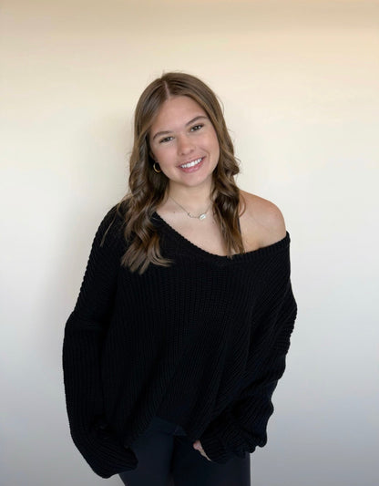 Woman wearing a black sweater against a plain background
