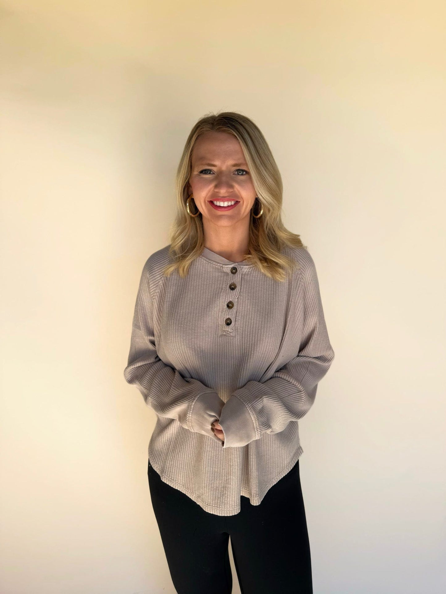 Woman wearing a dark taupe long-sleeve shirt against a plain background