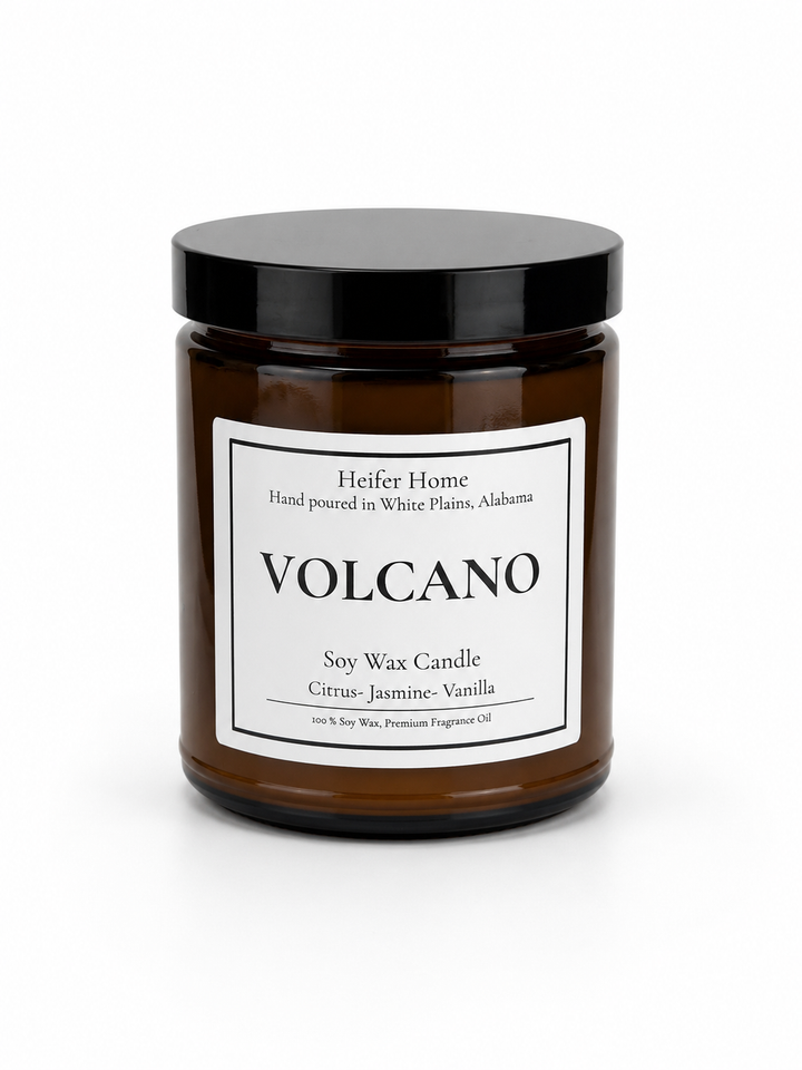 Heifer Home Volcano soy wax candle in an amber glass jar with a black lid featuring bright citrus, jasmine, and vanilla fragrance notes.